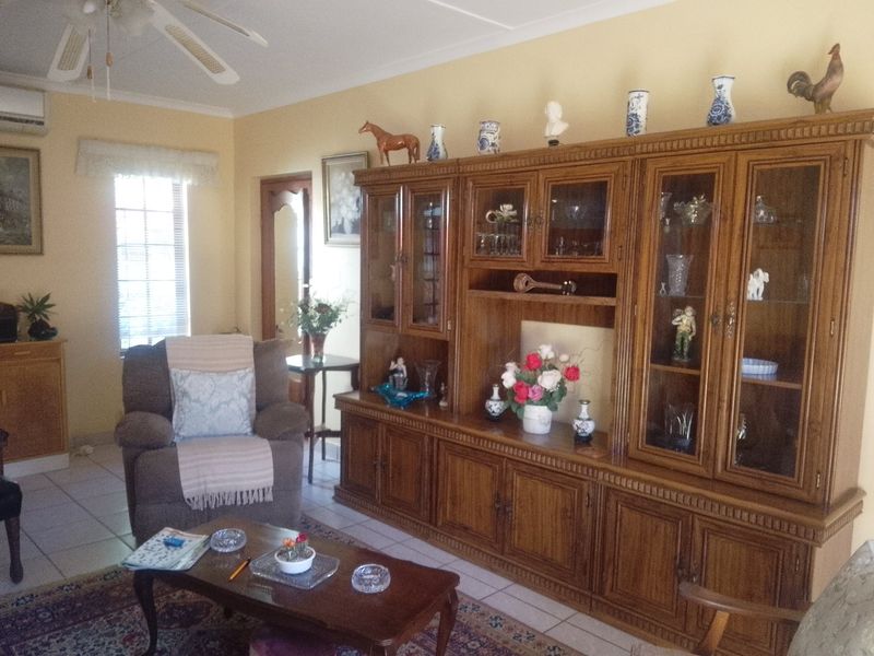 A living room featuring tiled flooring, a ceiling fan, and a wall-mounted air conditioning unit.