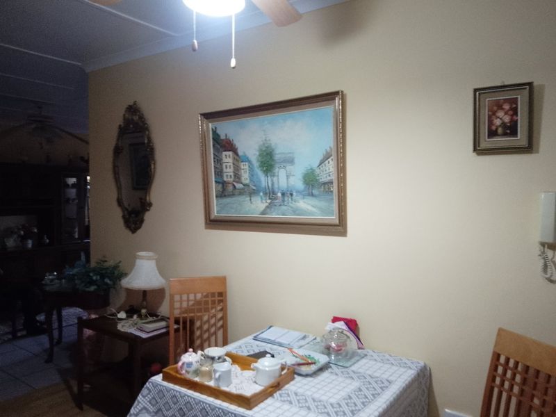 A dining area featuring a ceiling fan and wall-mounted intercom system, finished with neutral wall paint.