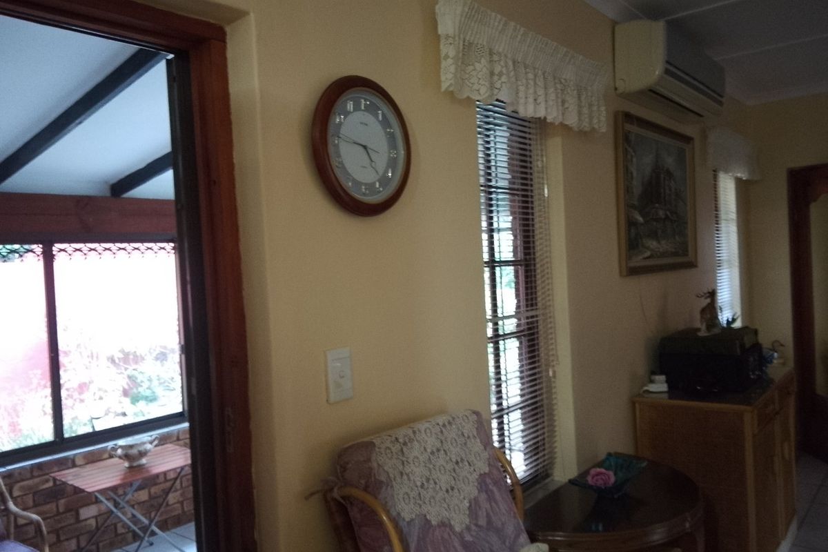 A living area featuring a split-system air conditioner, venetian blinds, and access to an adjacent patio space.