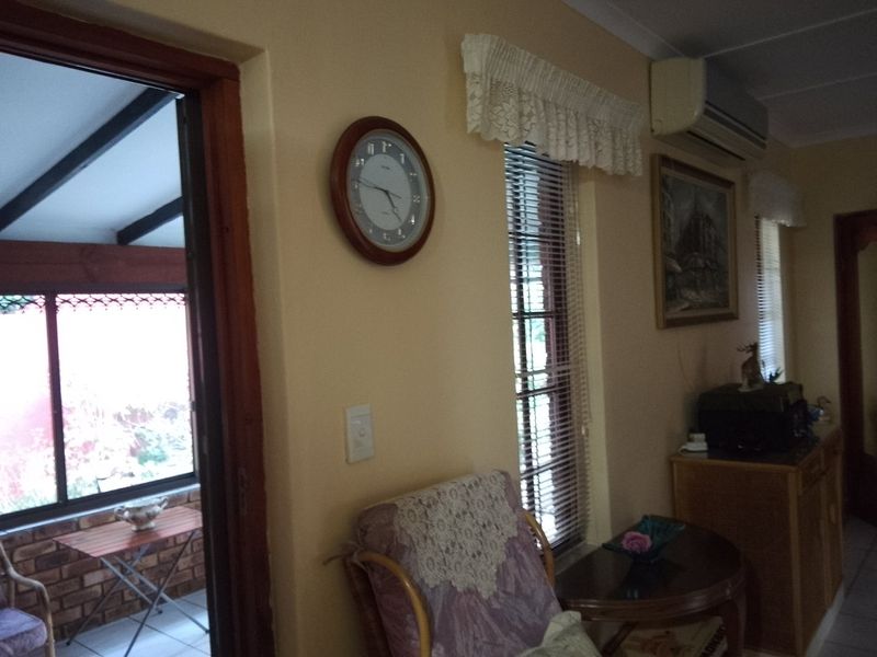 A living area featuring a split-system air conditioner, venetian blinds, and access to an adjacent patio space.