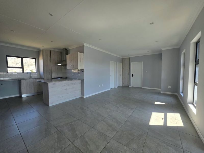 Spacious open-plan living area featuring a modern kitchen with stone countertops, built-in cabinetry, and neutral tiled flooring throughout.