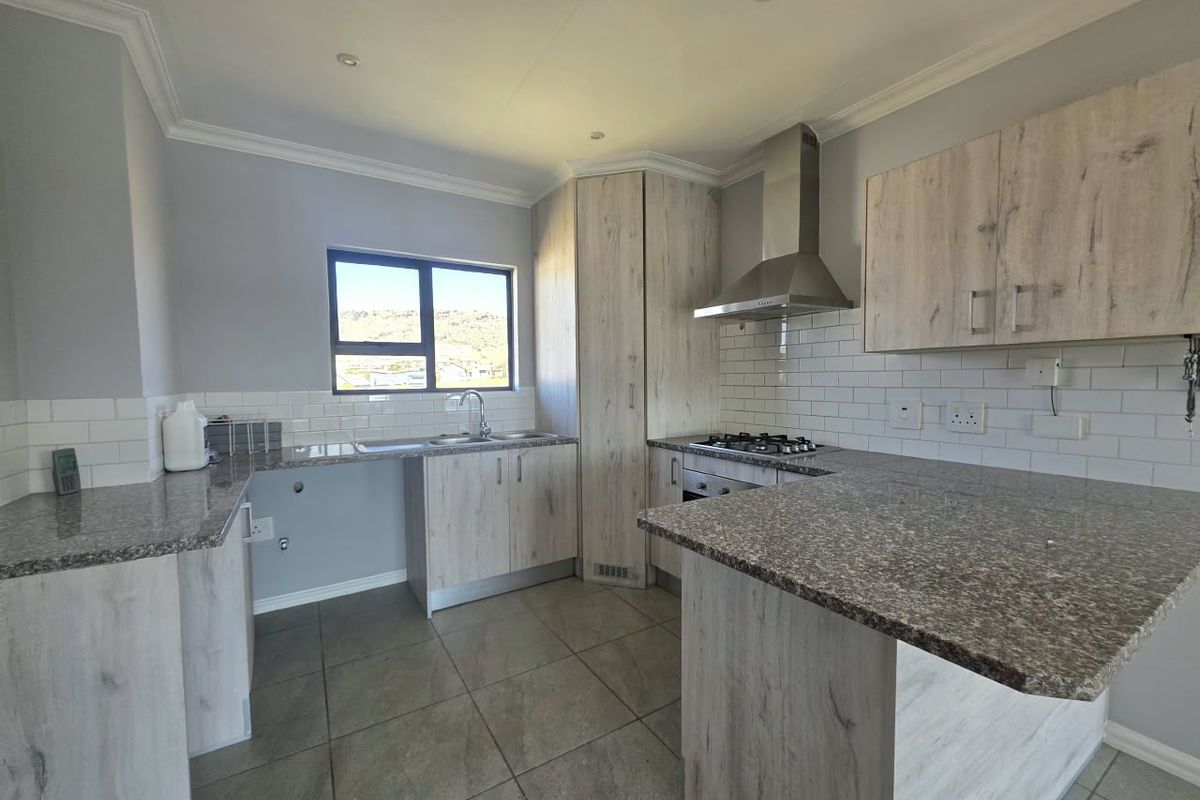 Modern kitchen featuring light wood-grain cabinetry, granite countertops, subway tile backsplash, and integrated stainless steel appliances, including a gas hob and extractor fan.