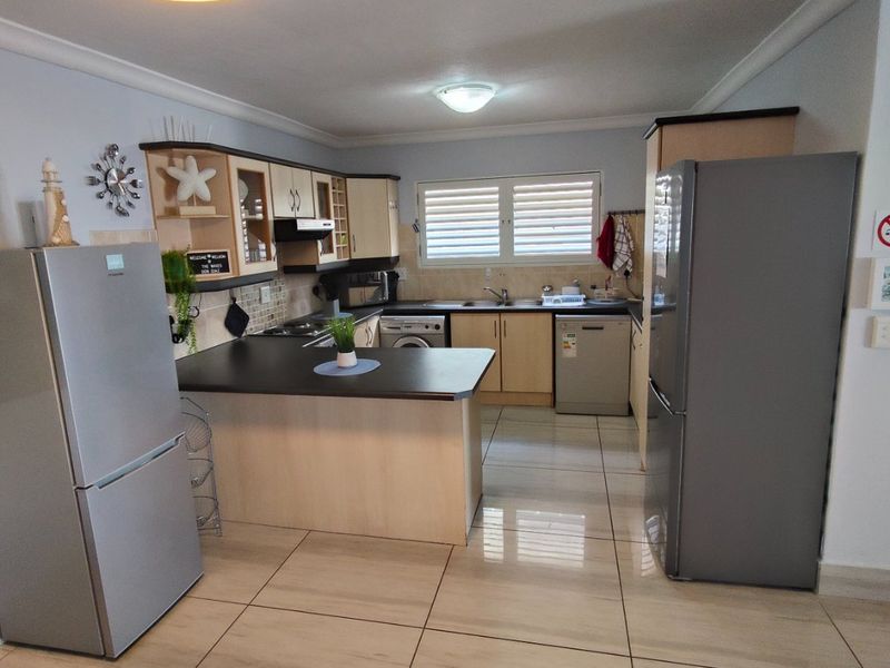 A functional kitchen featuring laminate cabinetry, dark countertops, tiled flooring, and integrated appliance spaces, offering a practical layout for daily use.