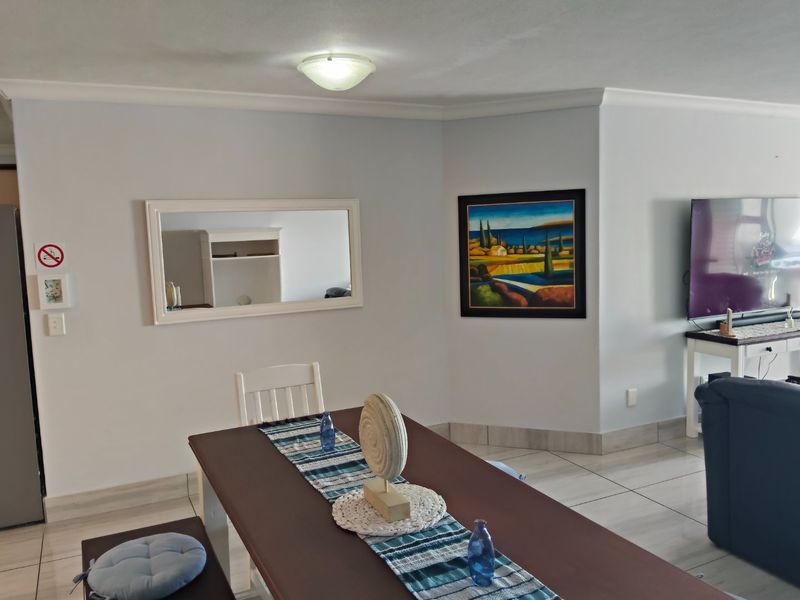 Open plan living and dining area featuring neutral tiled flooring and cove cornice detailing, creating a bright and functional living space.