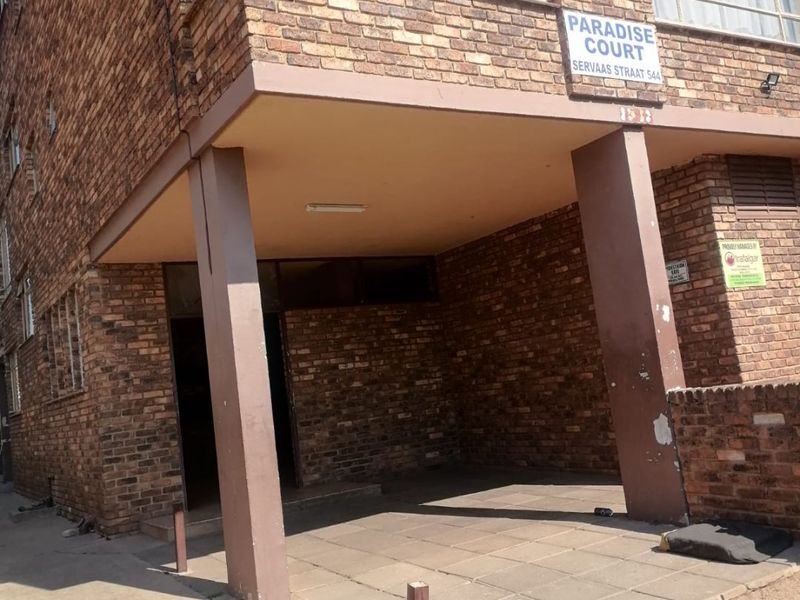 Front entrance area of Paradise Court apartment building featuring a face brick facade and paved covered walkway.