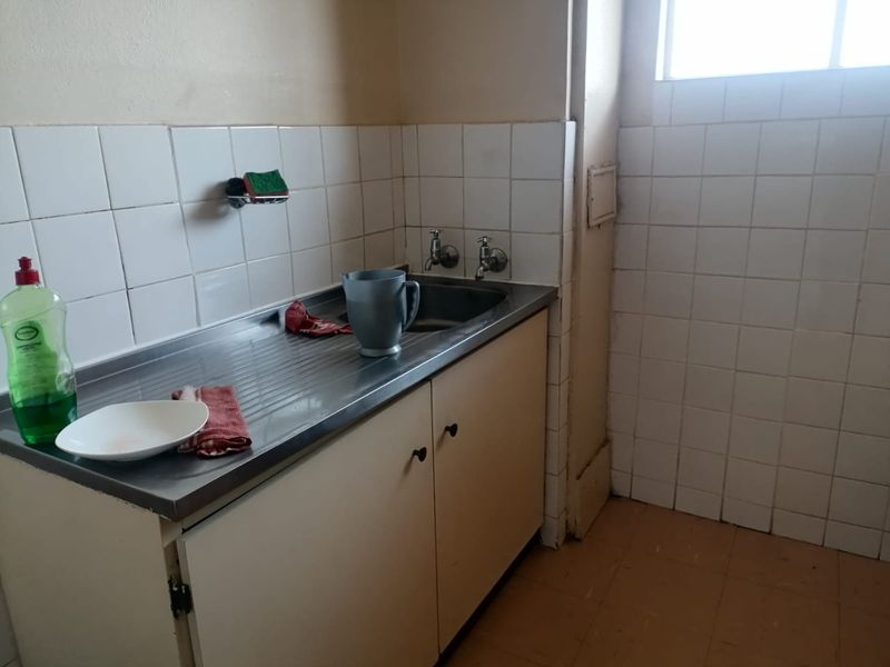A functional laundry area featuring a stainless steel sink, built-in cabinetry, and tiled splashbacks, offering a practical space for utility tasks.