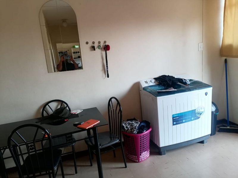 A functional laundry area featuring a wall-mounted mirror and basic utility space, suitable for laundry appliances and household tasks.