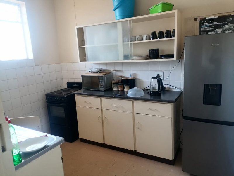 A functional kitchen featuring built-in cabinetry, a tiled backsplash, and a freestanding stove, offering a practical layout with potential for modern updates.