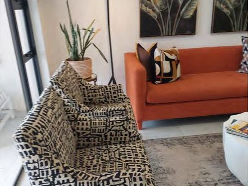A bright living room area featuring tiled flooring and a large sliding glass door providing access to the outdoor space.
