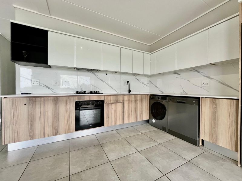 Modern kitchen featuring sleek white and wood-grain cabinetry, marble-look splashback, integrated oven, gas hob, and tiled flooring in a clean, contemporary layout.