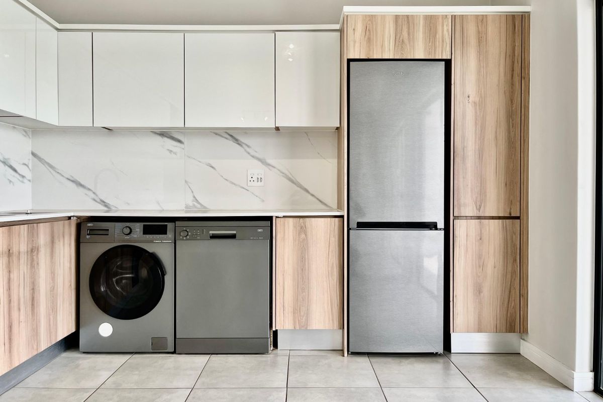 Modern kitchen featuring sleek white and wood-grain cabinetry, marble-look splashback, and integrated appliance housing with tiled flooring.