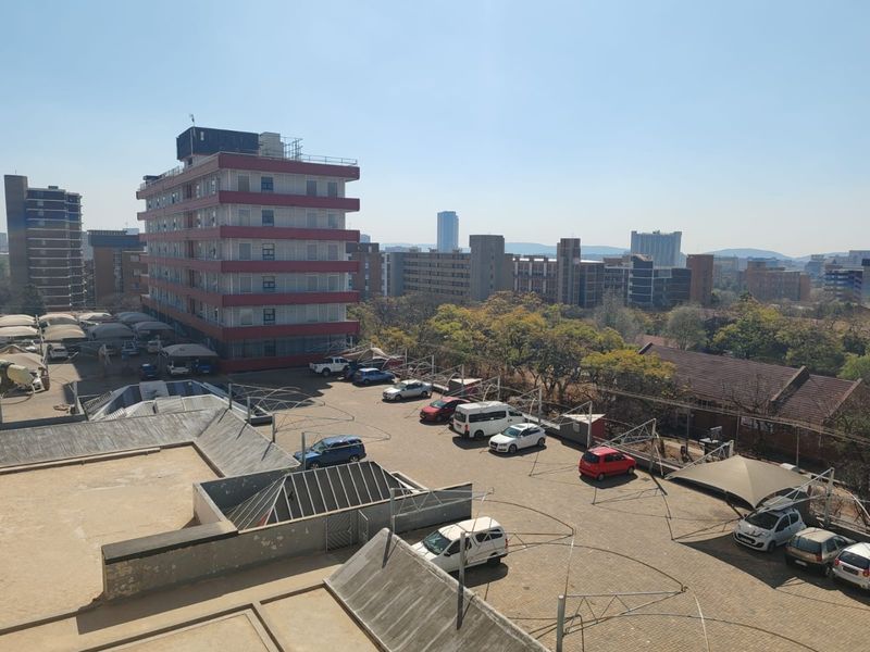 Elevated view overlooking a paved parking area with shade cloth carports and surrounding urban apartment buildings.