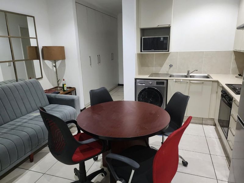 Open-plan living and kitchen area featuring tiled floors, built-in cabinetry, integrated appliances, and ample storage space.