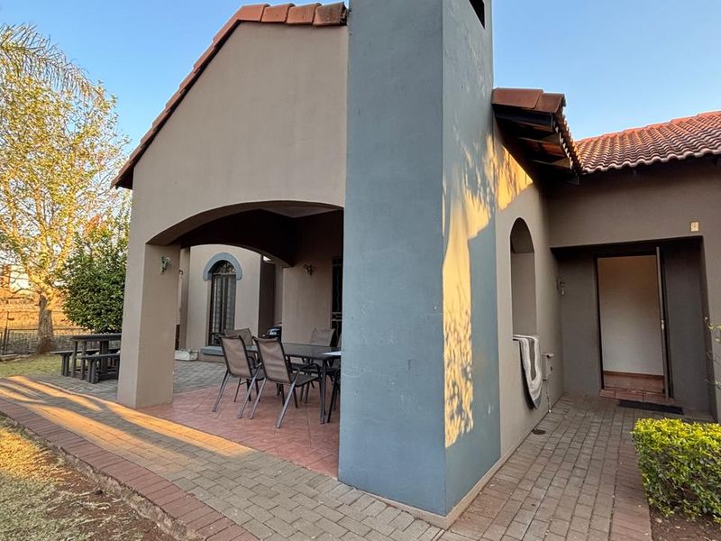 A covered patio area featuring tiled flooring and a prominent chimney stack, providing a functional outdoor space for relaxation and entertainment.