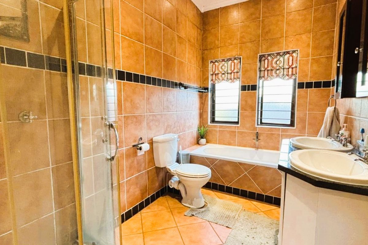 A functional bathroom featuring a shower enclosure, bathtub, and dual vanity with tiled finishes throughout.