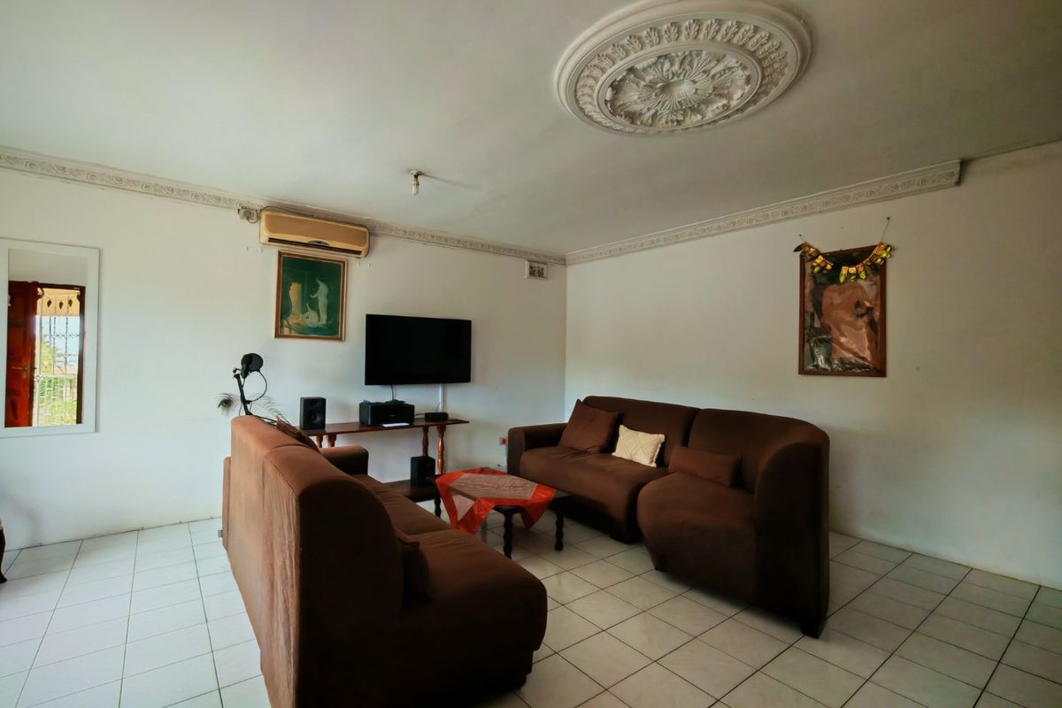 A living room featuring ceramic floor tiles, decorative crown molding, and a ceiling rose, equipped with a wall-mounted air conditioning unit.