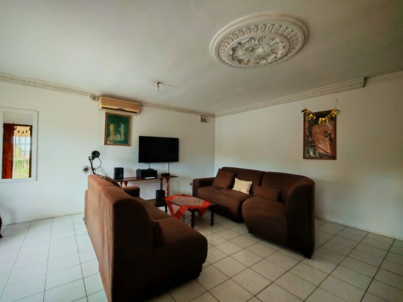 A living room featuring ceramic floor tiles, decorative crown molding, and a ceiling rose, equipped with a wall-mounted air conditioning unit.