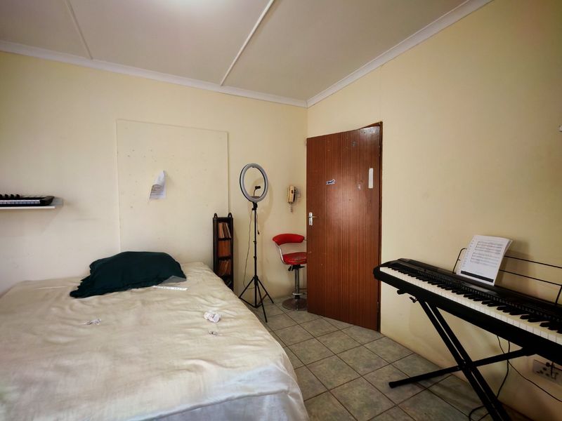 A bedroom featuring tiled flooring and a coved ceiling, requiring cosmetic updates to the wall finishes to improve its overall appeal.