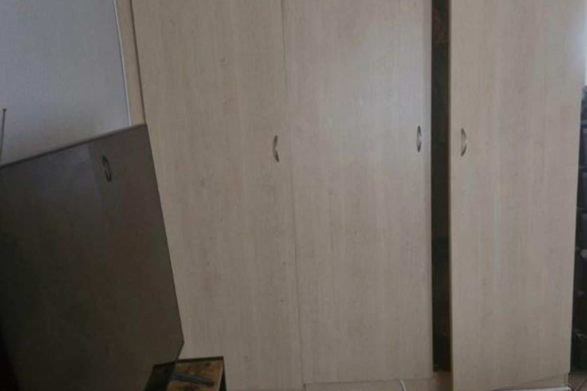 A bedroom featuring light wood-finish built-in wardrobes and tiled flooring.