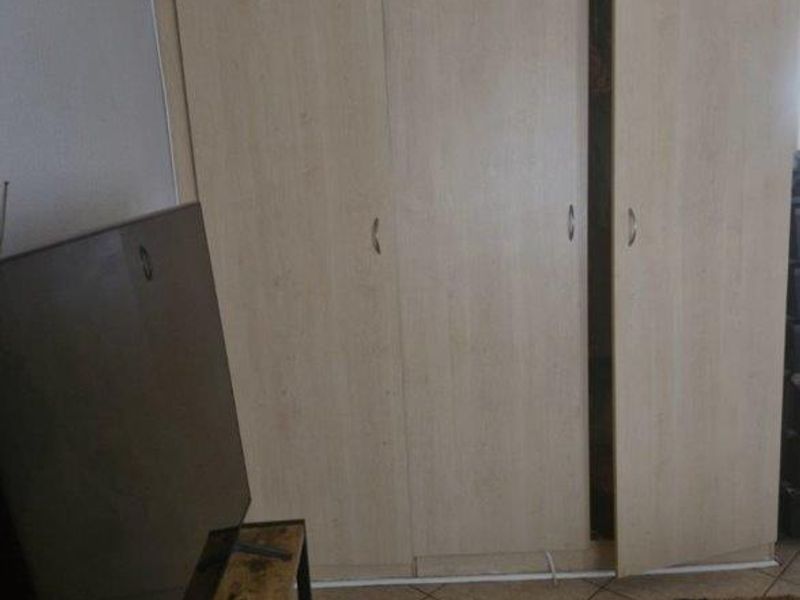 A bedroom featuring light wood-finish built-in wardrobes and tiled flooring.