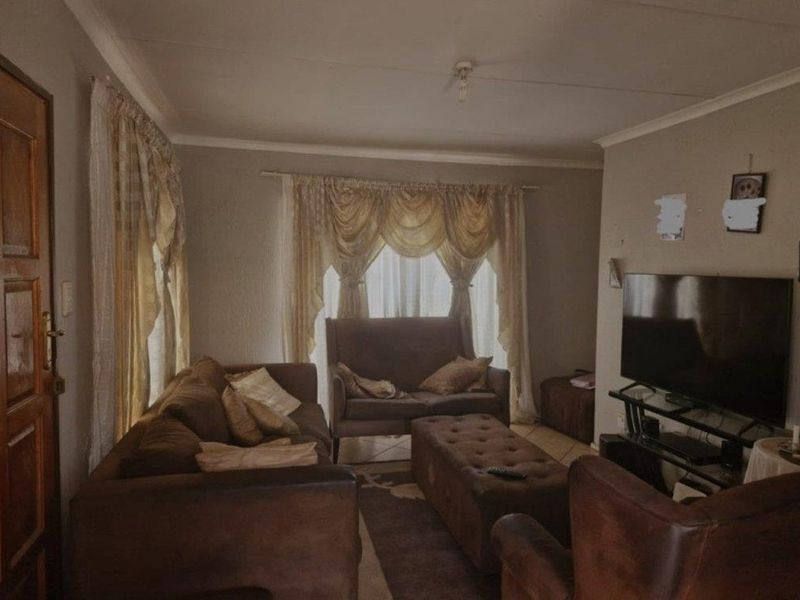 A living room featuring tiled flooring, a timber entrance door, and coved ceilings, providing a functional and comfortable space for relaxation.