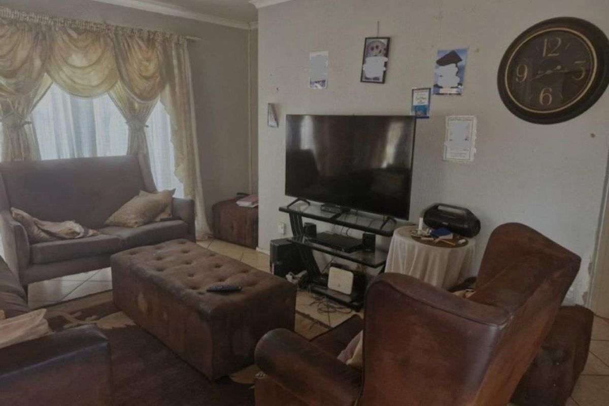 A living room featuring tiled flooring and curtain rails, showing signs of wear on the wall surfaces.