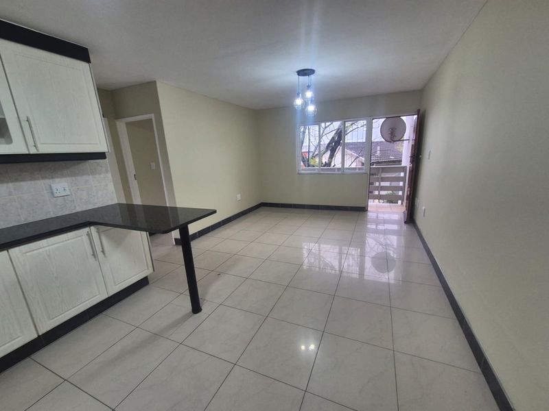 Open plan kitchen and living area featuring tiled flooring, modern cabinetry with granite countertops, and direct access to a private balcony.