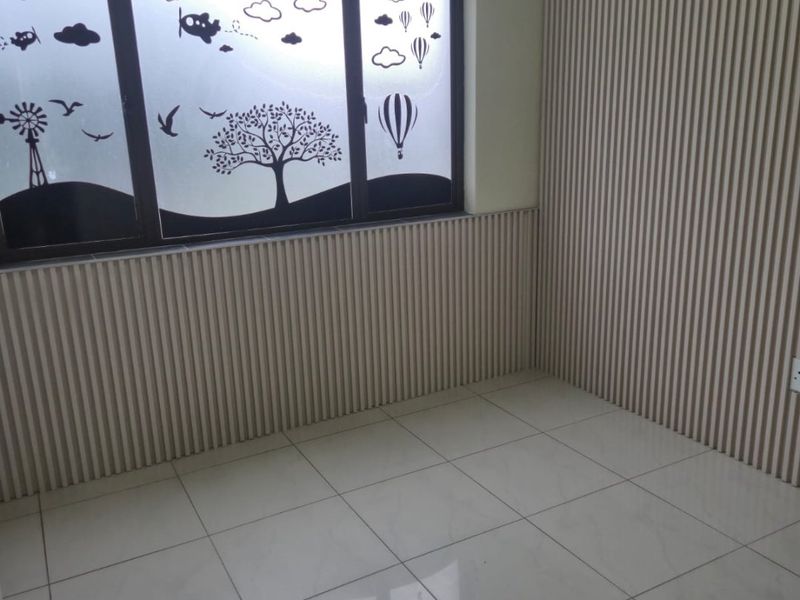 An empty bedroom featuring modern slatted wall paneling, large format tiled flooring, and a window with decorative frosted film.