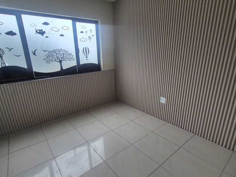 A bright, empty bedroom featuring modern slatted wood wall paneling and clean porcelain floor tiles, ready for personalization.