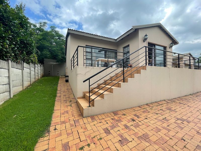 Rear view of the townhouse featuring a paved patio area, tiled staircase with metal railings, and sliding glass doors leading into the home.