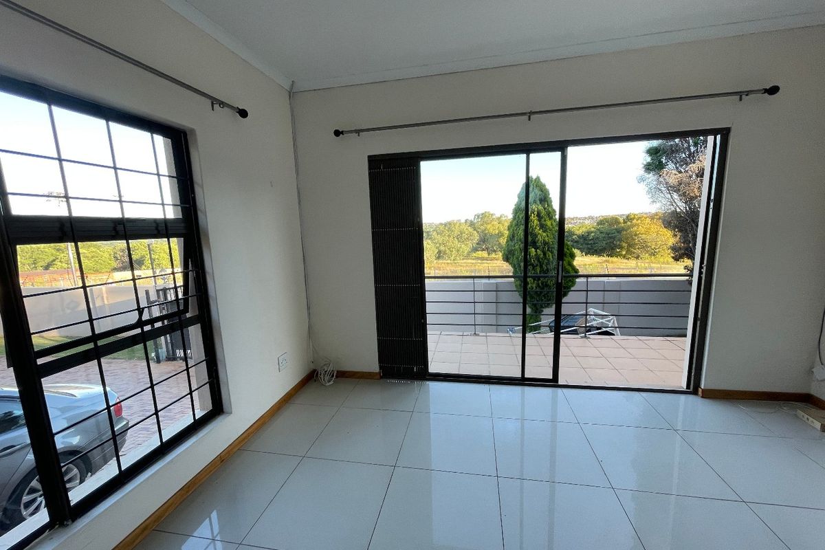 Bright and spacious living area featuring large windows, tiled flooring, and sliding glass doors that open onto an outdoor patio area.