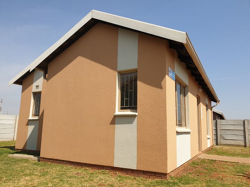 A well-maintained single-story residential house featuring a textured plaster facade, security bars on windows, and a surrounding precast concrete boundary wall.