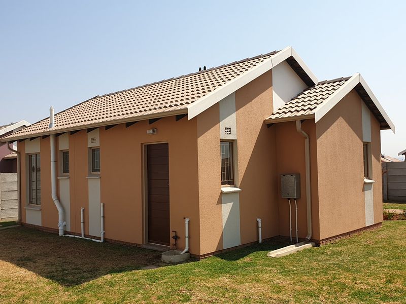 Rear view of a modern single-story house featuring a tiled roof, plastered exterior walls, and integrated security features.