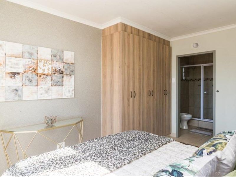 A well-maintained bedroom featuring built-in wooden cupboards and direct access to an en-suite bathroom.