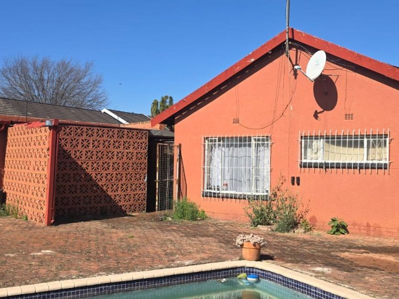 Rear exterior view of the house featuring a swimming pool, brick paved patio area, and security bars on windows.