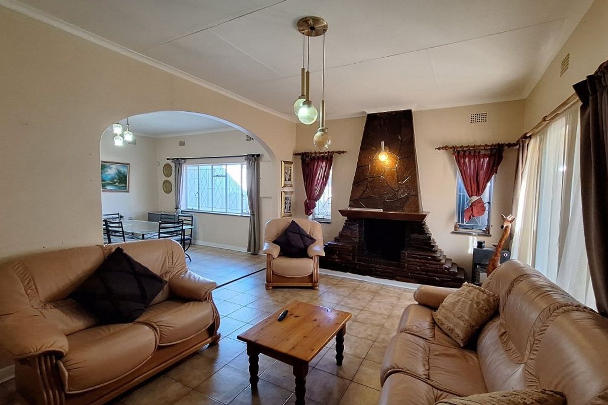 Spacious living room featuring a prominent stone fireplace, tiled flooring, and an open-plan archway leading to the adjacent dining area.