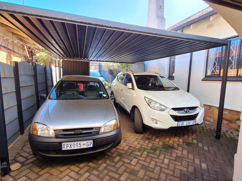 A covered carport area with paved flooring and metal roofing, providing secure off-street parking space.