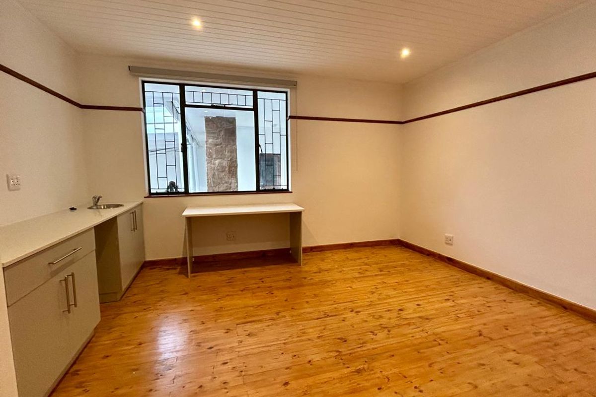 A spacious bedroom featuring polished timber flooring, built-in cabinetry, and a tongue and groove ceiling with recessed lighting.