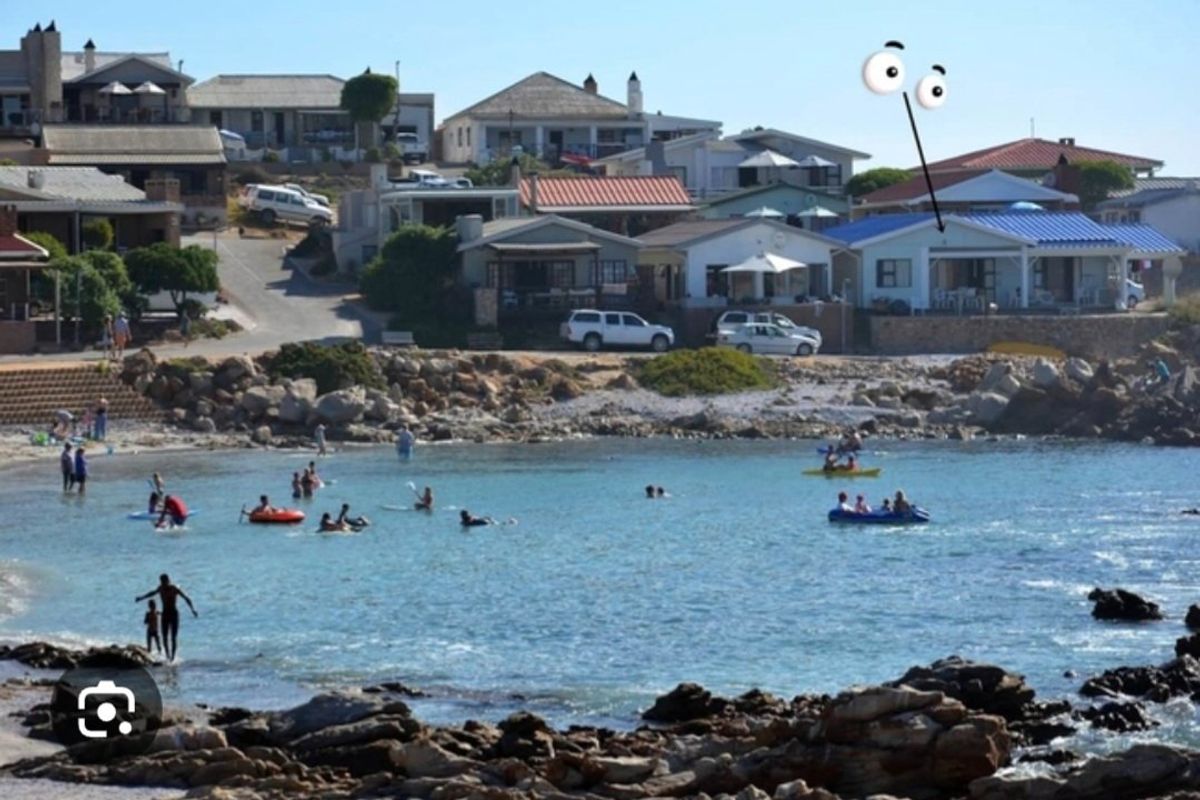 A scenic view of a coastal bay with rocky shoreline and residential properties situated along the waterfront.