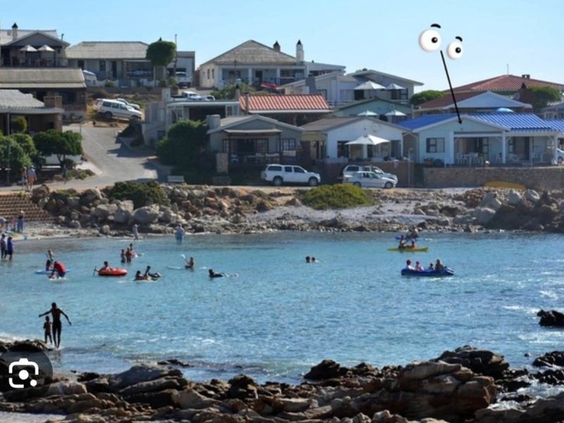 A scenic view of a coastal bay with rocky shoreline and residential properties situated along the waterfront.