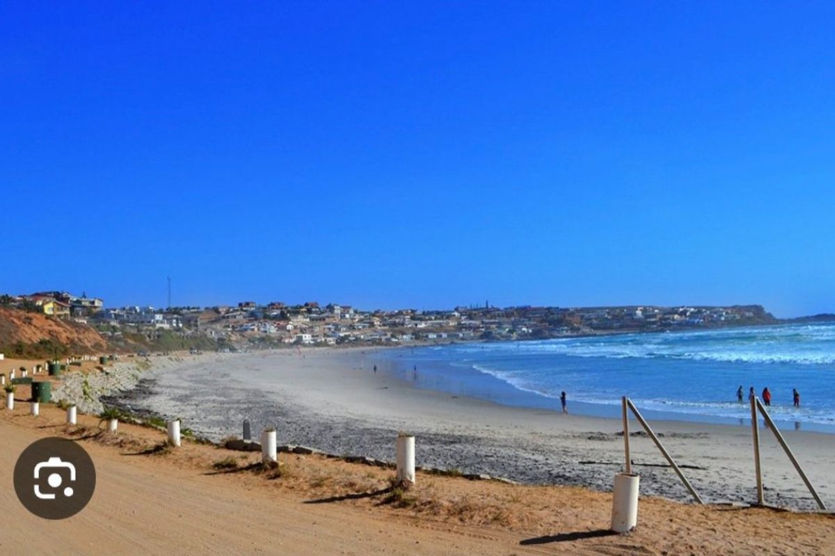 A scenic view of the coastline and beach, showcasing the surrounding residential area and natural landscape.