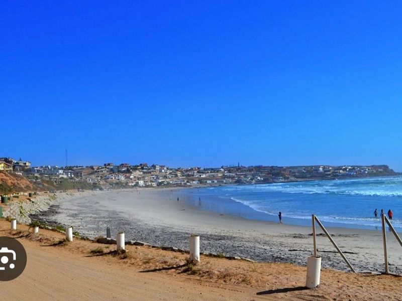 A scenic view of the coastline and beach, showcasing the surrounding residential area and natural landscape.