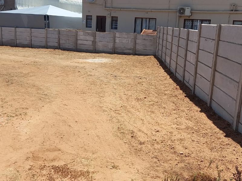 A vacant residential plot featuring a secure precast concrete boundary wall, offering a clear space ready for development.