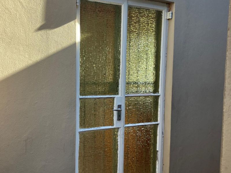 A rear exterior view showing a textured glass door with a metal frame and an external wall-mounted light fixture.