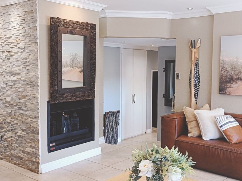 Open plan living area featuring a stone-clad fireplace, tiled flooring, recessed lighting, and built-in storage cupboards.