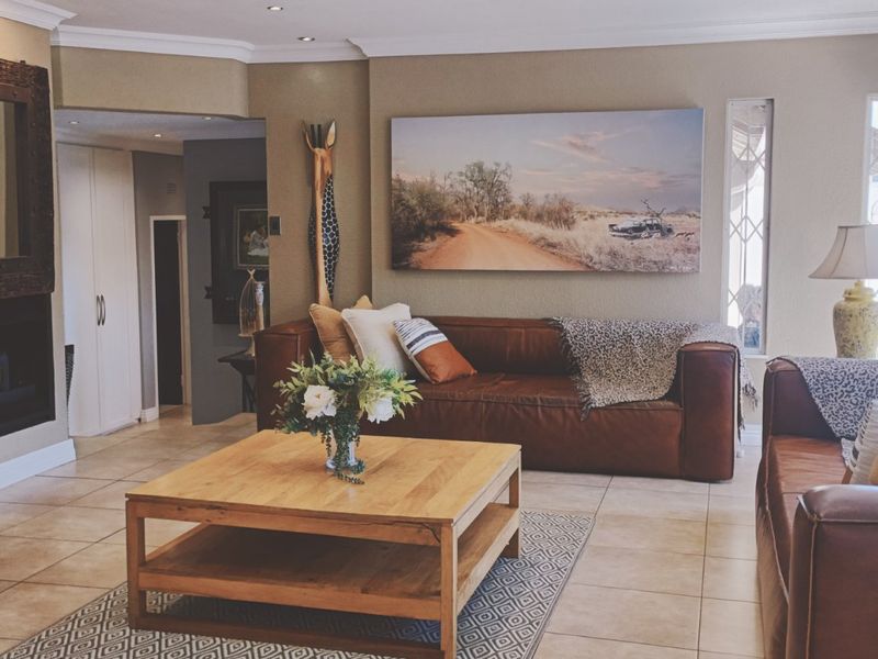 Spacious living room featuring a stone-clad fireplace, tiled flooring, and recessed lighting, creating a warm and inviting atmosphere.
