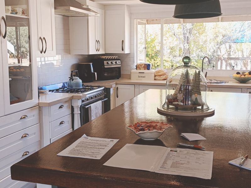 A well-maintained kitchen featuring a large central island, white cabinetry, gas stove, and a tiled backsplash with views to the garden.