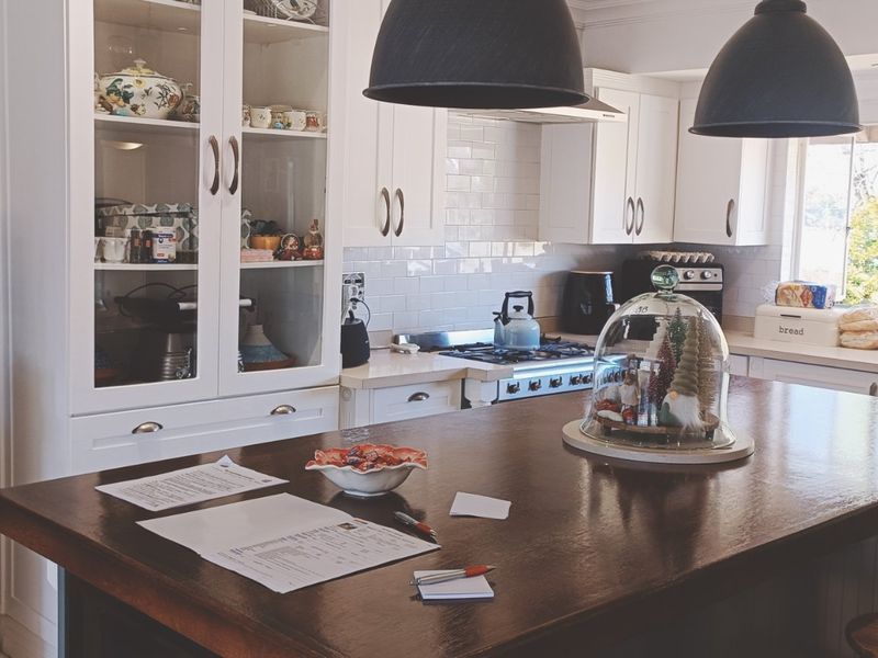 A well-maintained kitchen featuring a large central island, white cabinetry, subway tile backsplash, and integrated gas cooking appliances with ample storage.