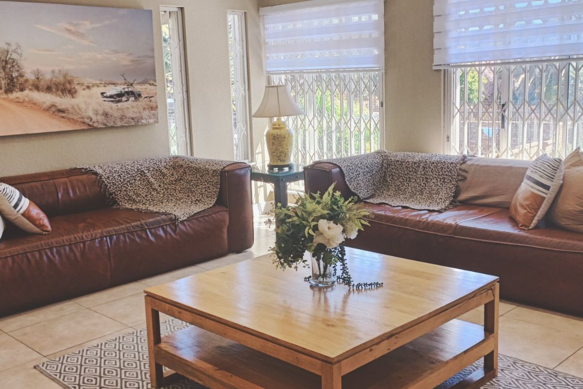 A comfortable living room featuring tiled flooring, secure window gates, and modern roller blinds, creating a bright and functional space.