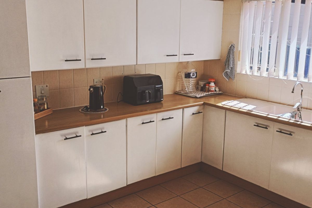A functional kitchen featuring white cabinetry, laminate countertops, tiled backsplash, and a double basin sink with a mixer tap.